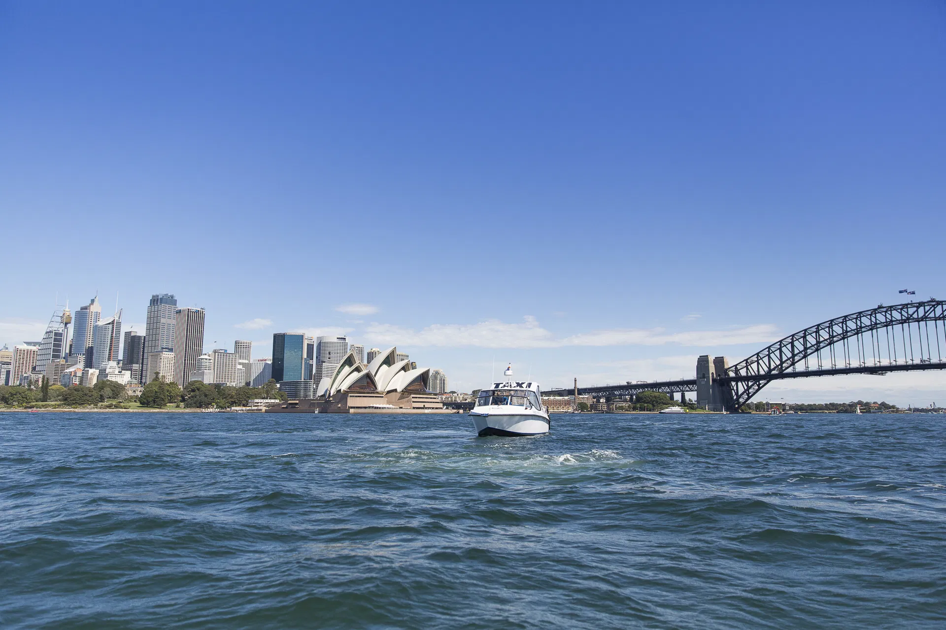 The Sydney Harbour bridge with a water taxi gliding underneath