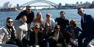Corporate group on the deck of a Majestic water taxi with the Harbour Bridge behind